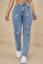 Embroidered blue jeans front view against beige stone background