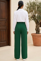 Olive green tie-waist trousers styled with a white long-sleeve blouse, rear view on a terrace