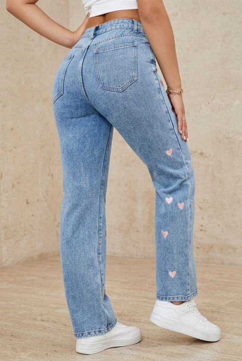 Embroidered blue jeans back view against beige stone background