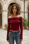 Rouge burgundy off-shoulder sweater in a stone courtyard