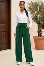 Olive green tie-waist trousers styled with a white long-sleeve blouse, front view on a terrace